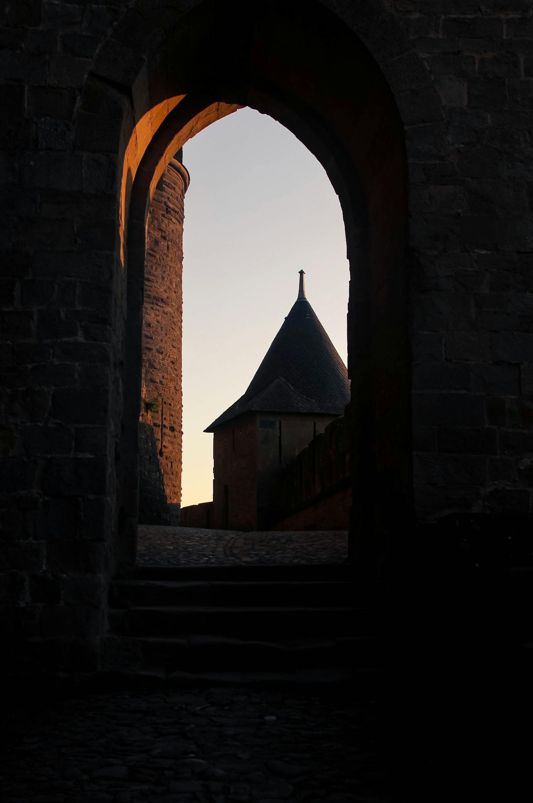 Capture the magic of Carcassonne's medieval architecture at twilight through a historic arched gateway.